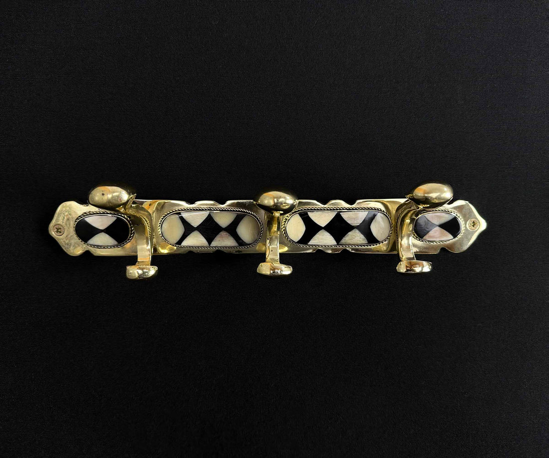 Multiple handcrafted brass wall hooks displayed on a wall.