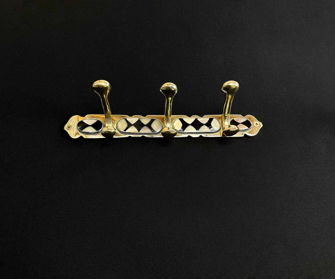 Close-up of handcrafted brass wall hooks with bone and resin inlay