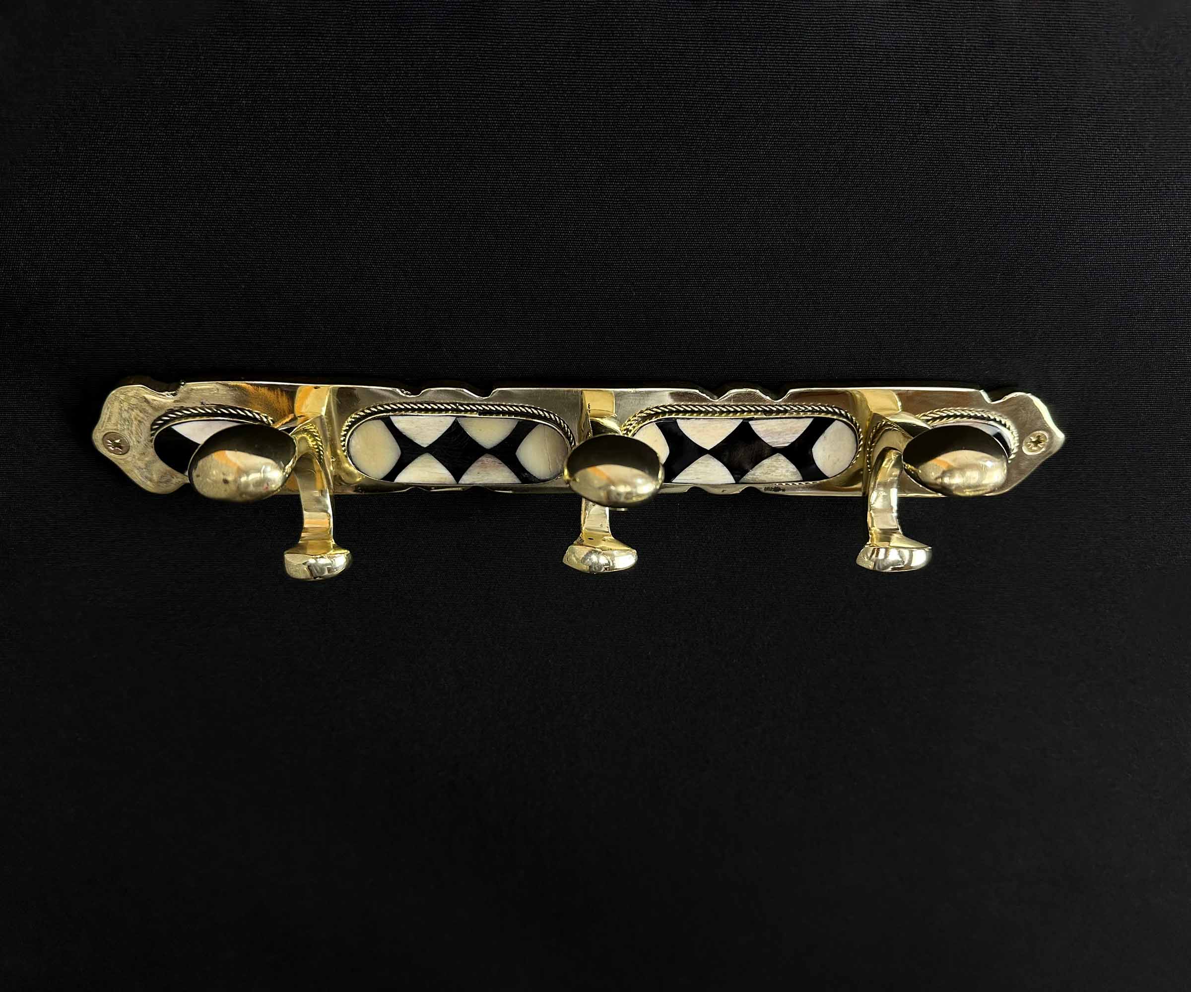 Elegant detailing of handcrafted brass wall hook with bone and resin inlay.