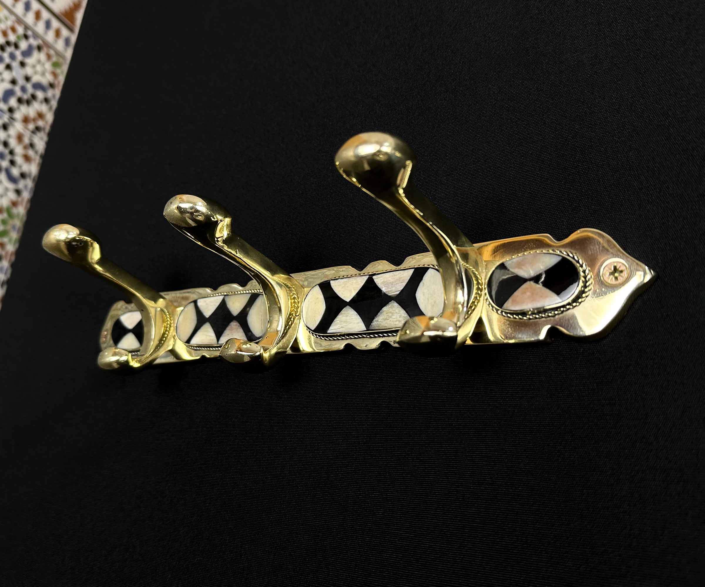 Installation of handcrafted brass wall hooks on a wall.